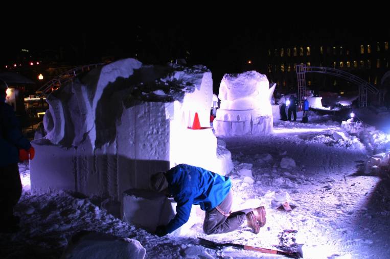 Escultores de nieve trabajando de noche en el Carnaval de Quebec.
